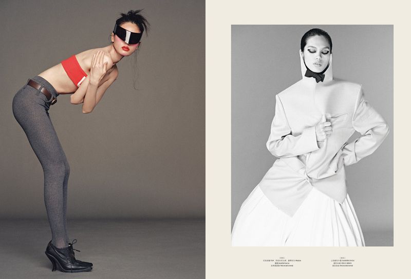 Fashion editorial shot featuring a woman in a red top and gray tights, complemented by another woman in a white suit, against a plain gray backdrop.