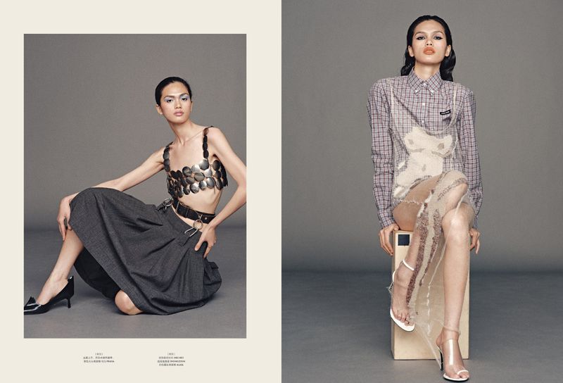 Two women strike stylized poses in a fashion layout against a neutral background, one seated on the floor, the other on a cube.
