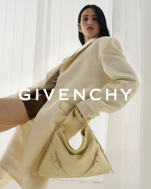 Elegant woman posing in a cream-colored blazer, holding a matching handbag, fashion, and portrait photography.