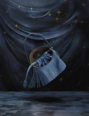 Elegant blue leather bucket bag with drawstring closure and a fringe detail, highlighted against a dark blue, star-studded backdrop.