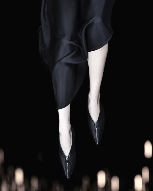 Close-up of black dress and black zipper flats on a model, set against a blurred, dark background with bokeh lights.