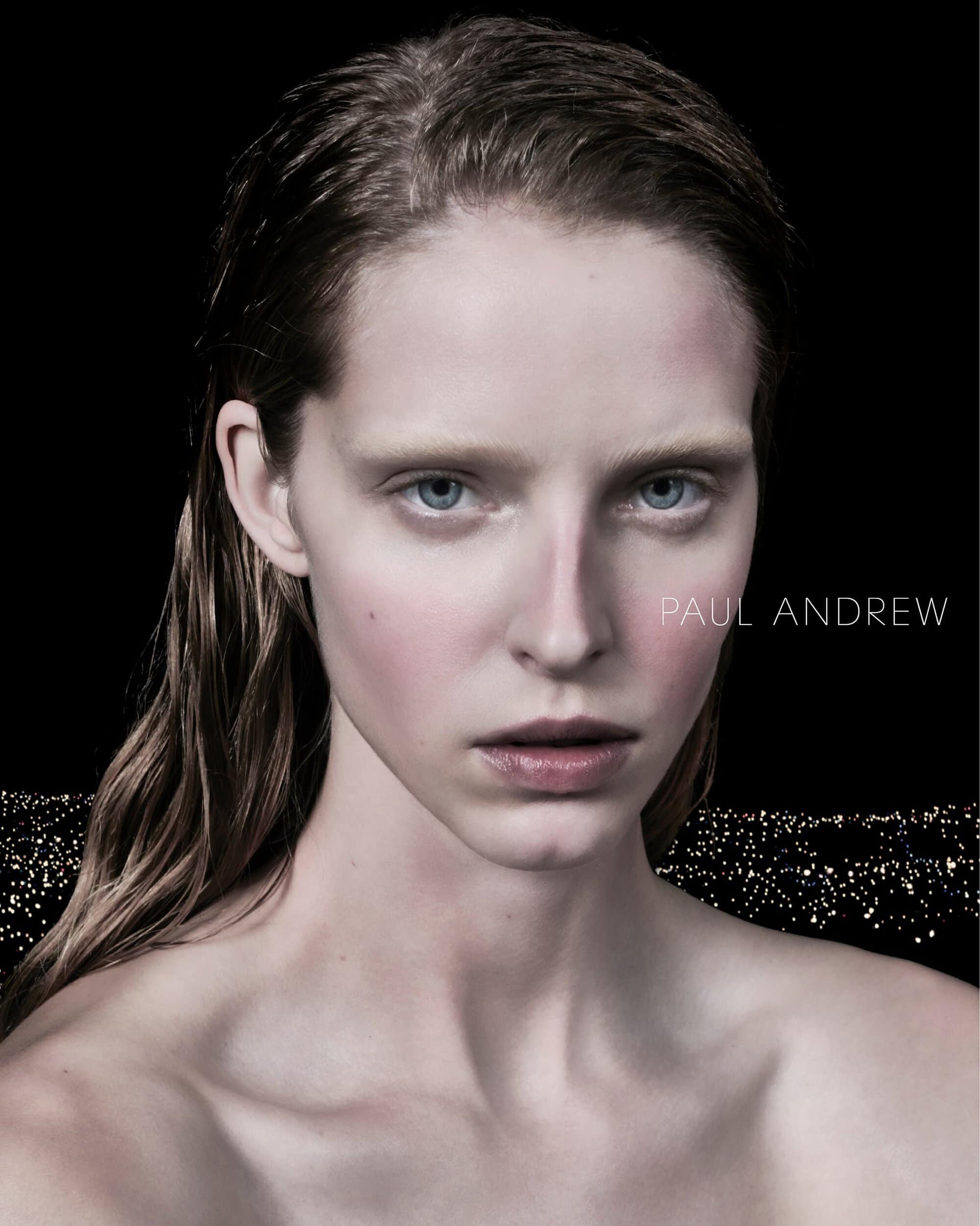 Close-up studio portrait of a fair-skinned adult female with wet hair against a dark background with bokeh.