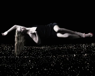 Model Abby Champion floating horizontally in a black dress over a field of golden lights for Paul Andrew Lucid Dreaming campaign.