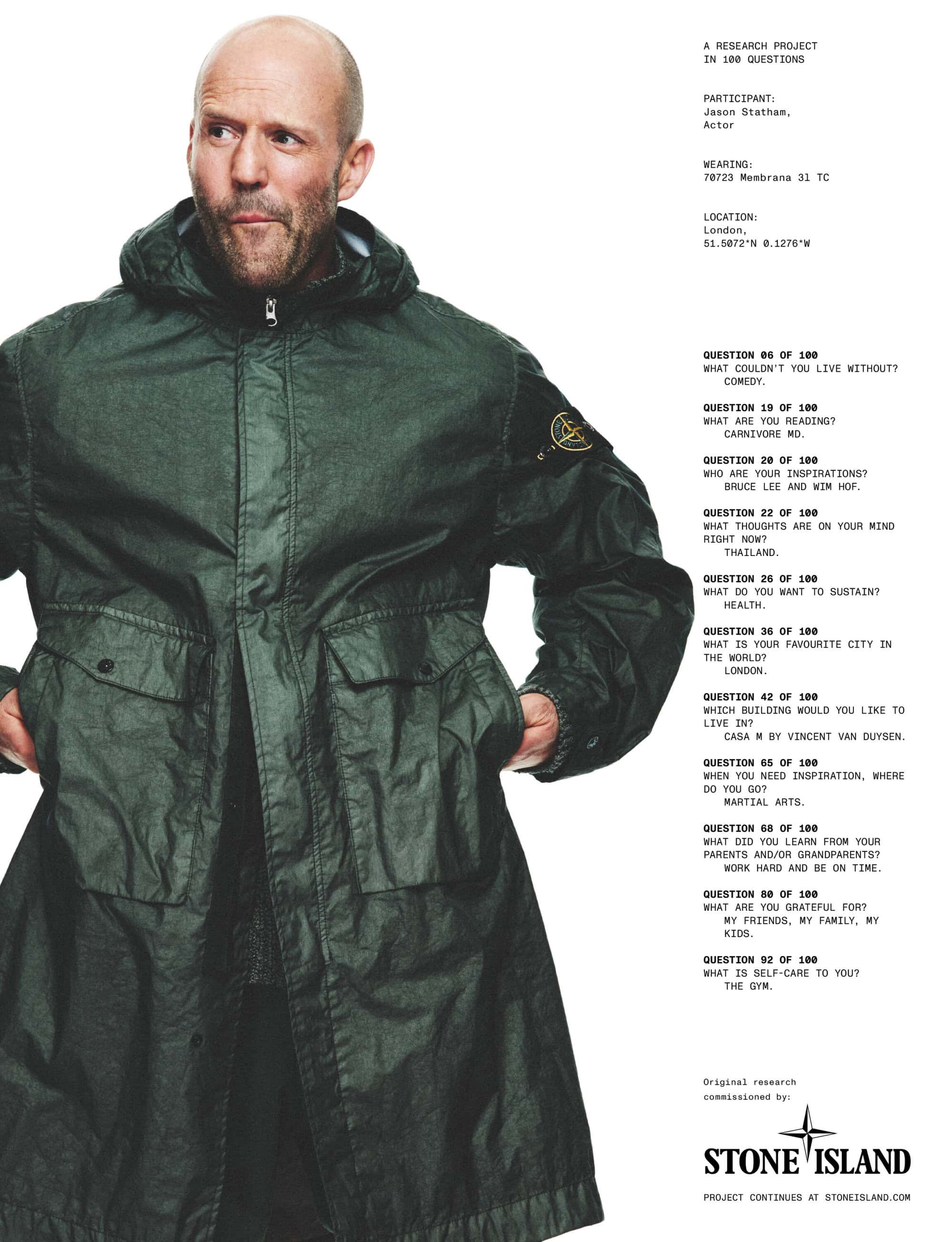 Jason Statham poses in a dark green hooded jacket against a clean white backdrop, showcasing the Stone Island brand and fashion aesthetic.