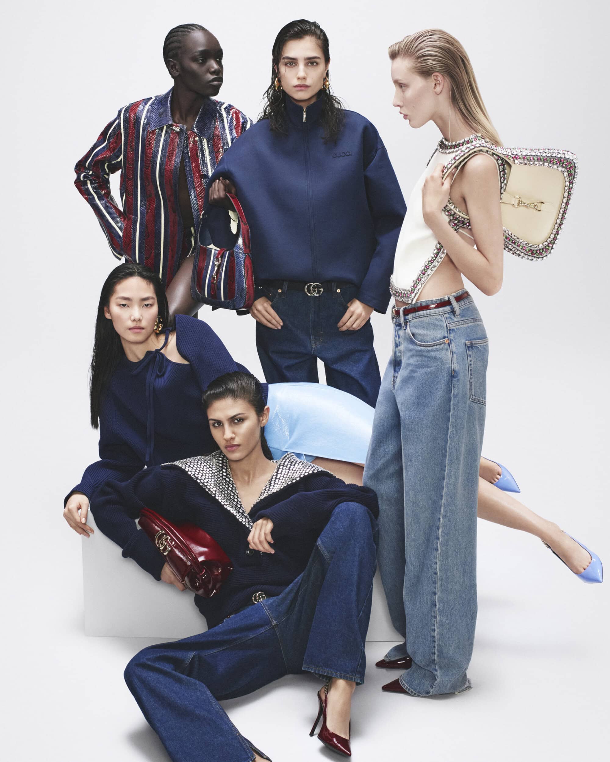 Group fashion shot: Five diverse women in stylish denim and navy apparel are posed against a light background in a visually striking composition.