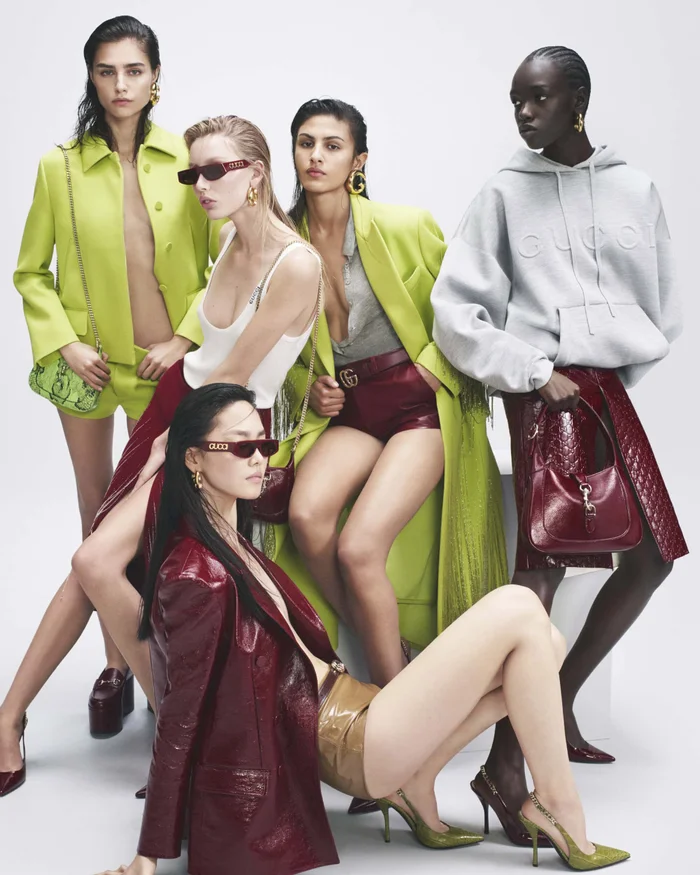 Group of five female models posing in Gucci Ancora 2024 campaign against white background wearing lime jackets and burgundy patent leather