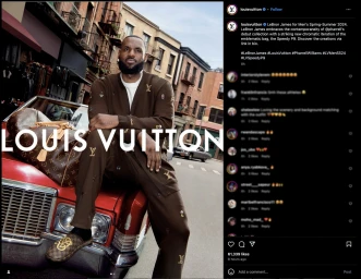 LeBron James leaning against a red vintage car wearing a brown monogram cardigan and trousers on a city street.