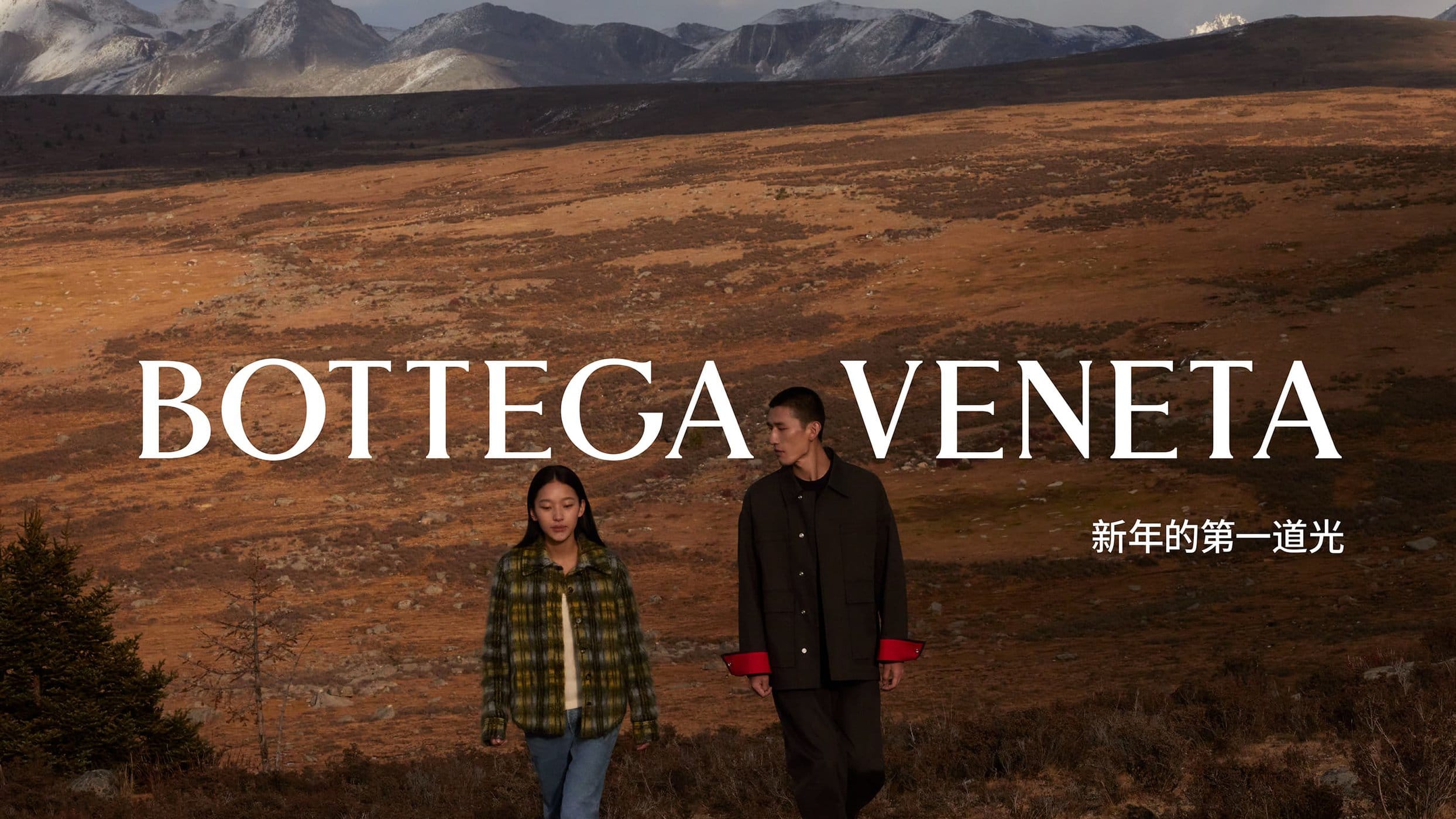 A man and a woman walking across a rugged mountain landscape under a wide sky for Bottega Veneta.