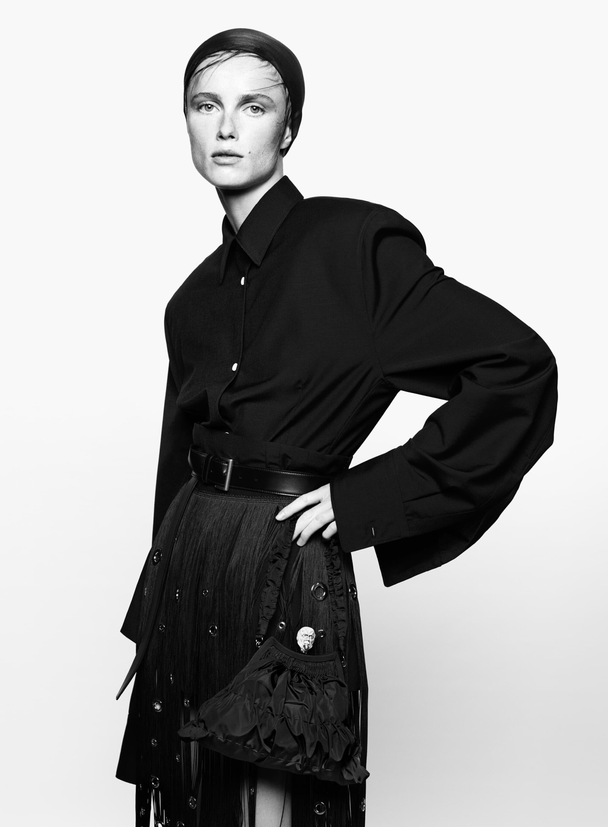 Black and white studio portrait of a woman in a black button-down shirt and skirt, with a smooth hairstyle and direct gaze.