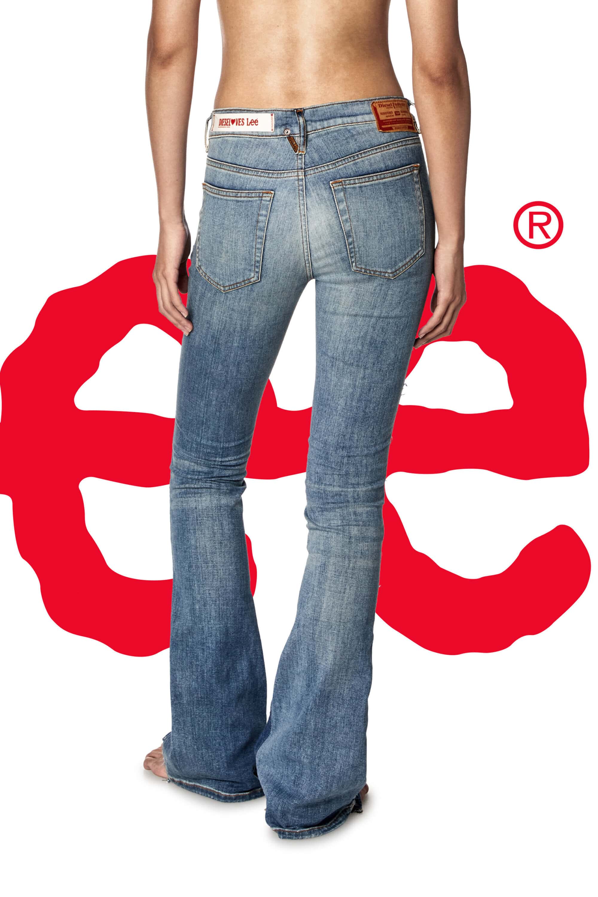 Back view of a woman wearing blue denim jeans with a red logo on a white background. The jeans have a slight bootcut flare.