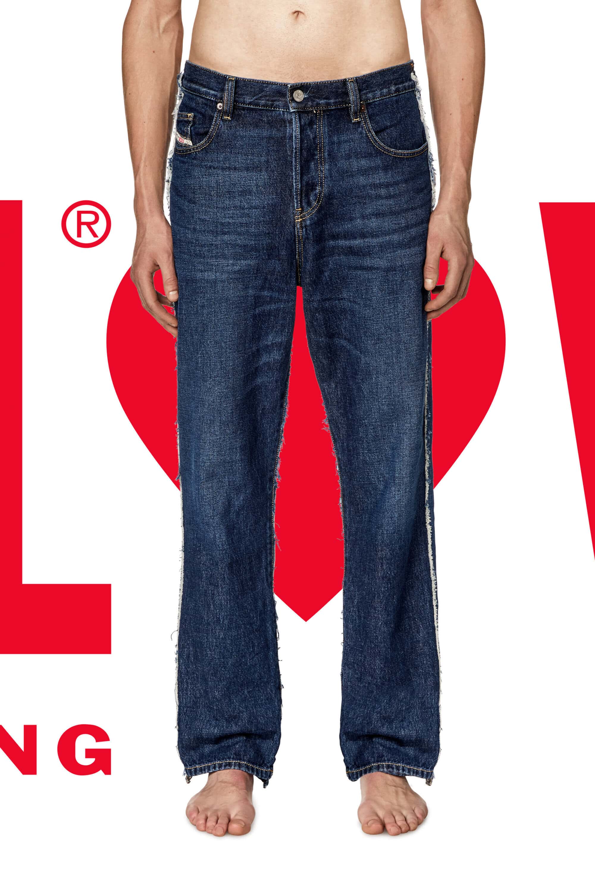 A man stands facing forward, modeling dark wash jeans with a white stripe, set against a white backdrop with graphic red heart elements.
