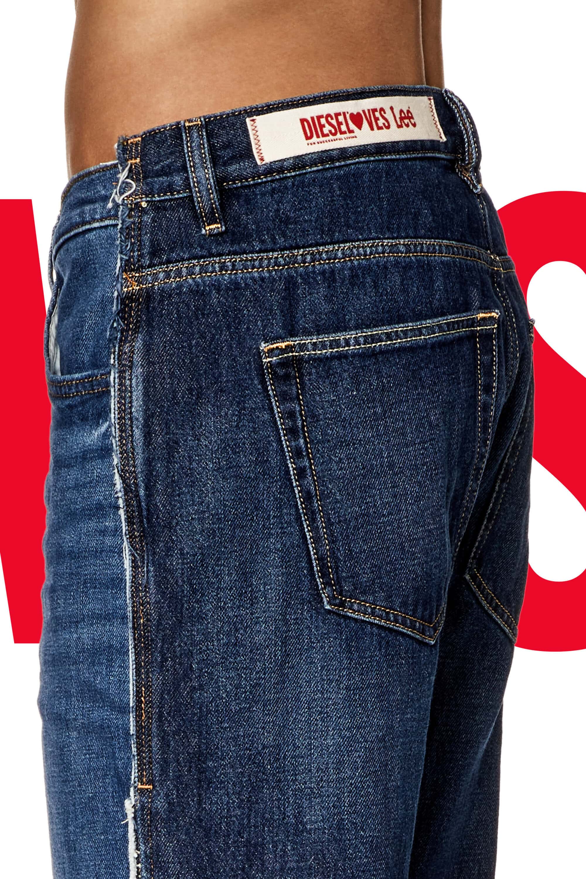 Close-up of a person wearing dark wash jeans, featuring a Diesel Loves Lee branded tag, against a partially red and white background.