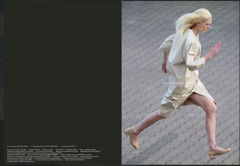 Fashion shot of androgynous fair-skinned adult running outdoors wearing beige tunic dress and beige ballet shoes on concrete surface.