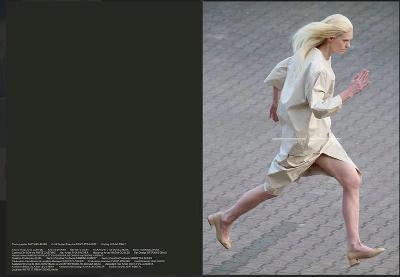 Fashion shot of androgynous fair-skinned adult running outdoors wearing beige tunic dress and beige ballet shoes on concrete surface.