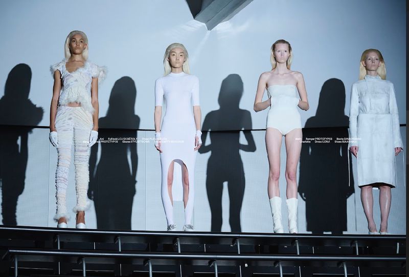 Runway models in all-white ensembles, standing on a stage with geometric lighting and long shadows, showcasing minimalist fashion.