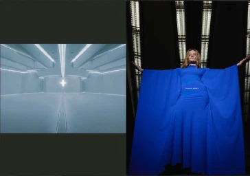 Model wearing a vibrant blue long-sleeved gown with dramatic draped sleeves posed against an architectural backdrop with vertical lights.