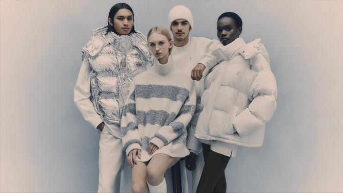 Four models in winter outerwear including a metallic puffer vest and white puffer jacket against a grey background.