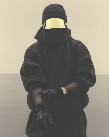 Person in black balaclava and gold visor, close-up studio shot on neutral backdrop, wearing a black hooded sweatshirt and gold watch.