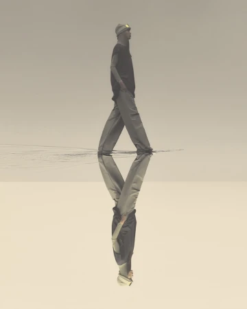 A man walks in shallow water, wearing casual clothes and a beanie, reflected in the water's surface against a neutral sky.