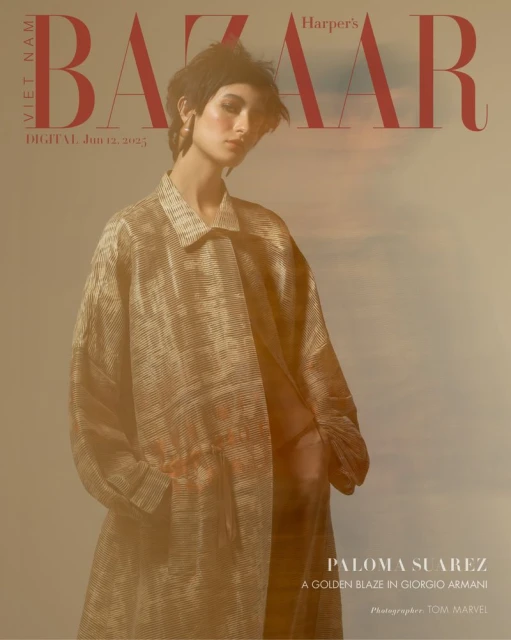 Fashion editorial featuring a woman in a gold coat for Harper's Bazaar, posing against a soft-focus cloud backdrop with the magazine's masthead.