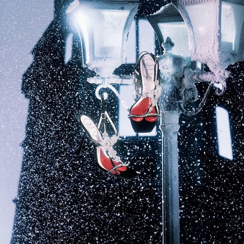 Elegant high heels hanging from a vintage lamp post, dusted with snow, against a softly blurred, snow-flecked dark background.