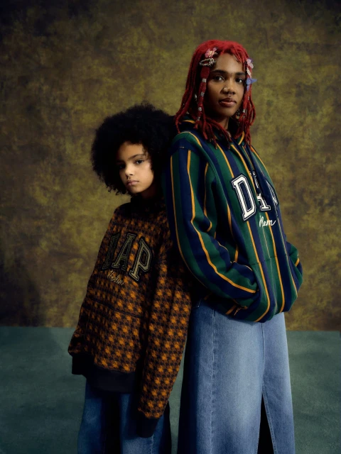 Two people, a child and an adult, in a studio shot wearing Gap clothing. The child has an afro and the adult has dyed red hair.