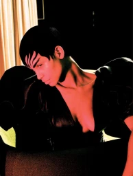 Model with dark styled hair in a black top lit with dramatic red light for Vogue Brasil editorial