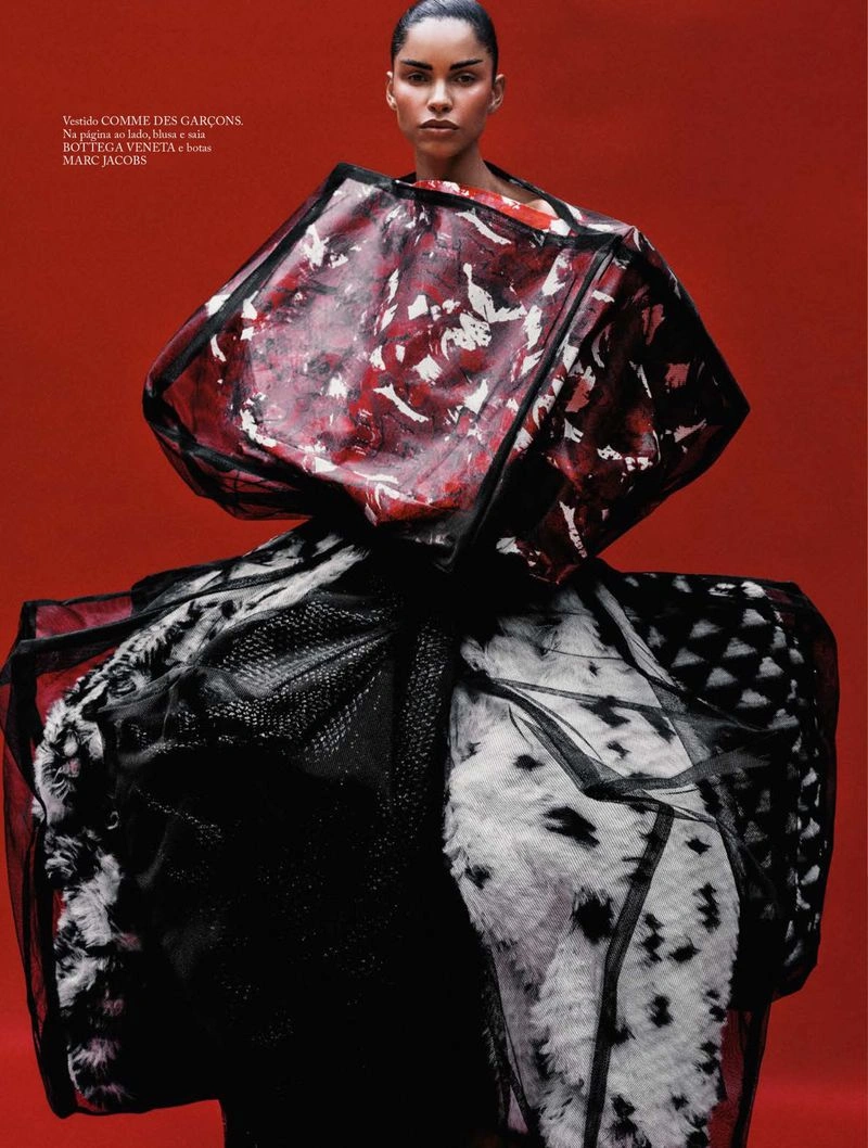 Model in voluminous sculptural avant-garde garment against a solid red backdrop for Vogue Brasil editorial