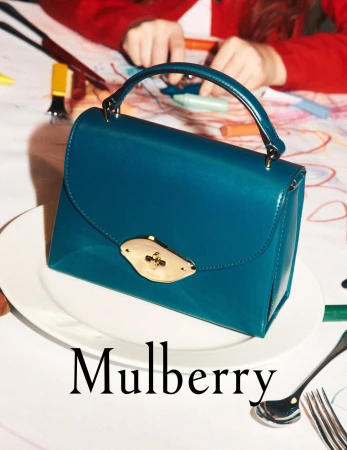 Turquoise Mulberry handbag on a white plate, with a child drawing in the background, showcasing fashion and family lifestyle.