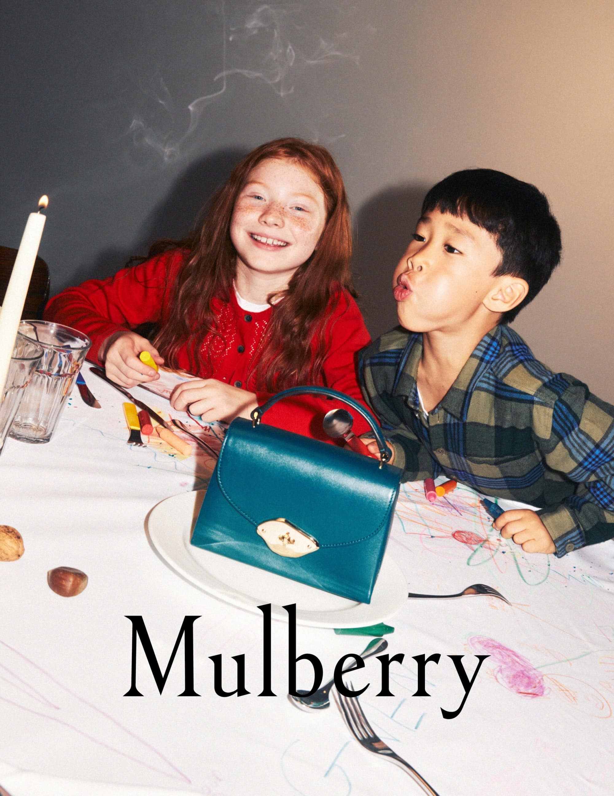Two children, a girl and a boy, seated at a table with a teal handbag, drawing with crayons, create a vibrant and playful image.