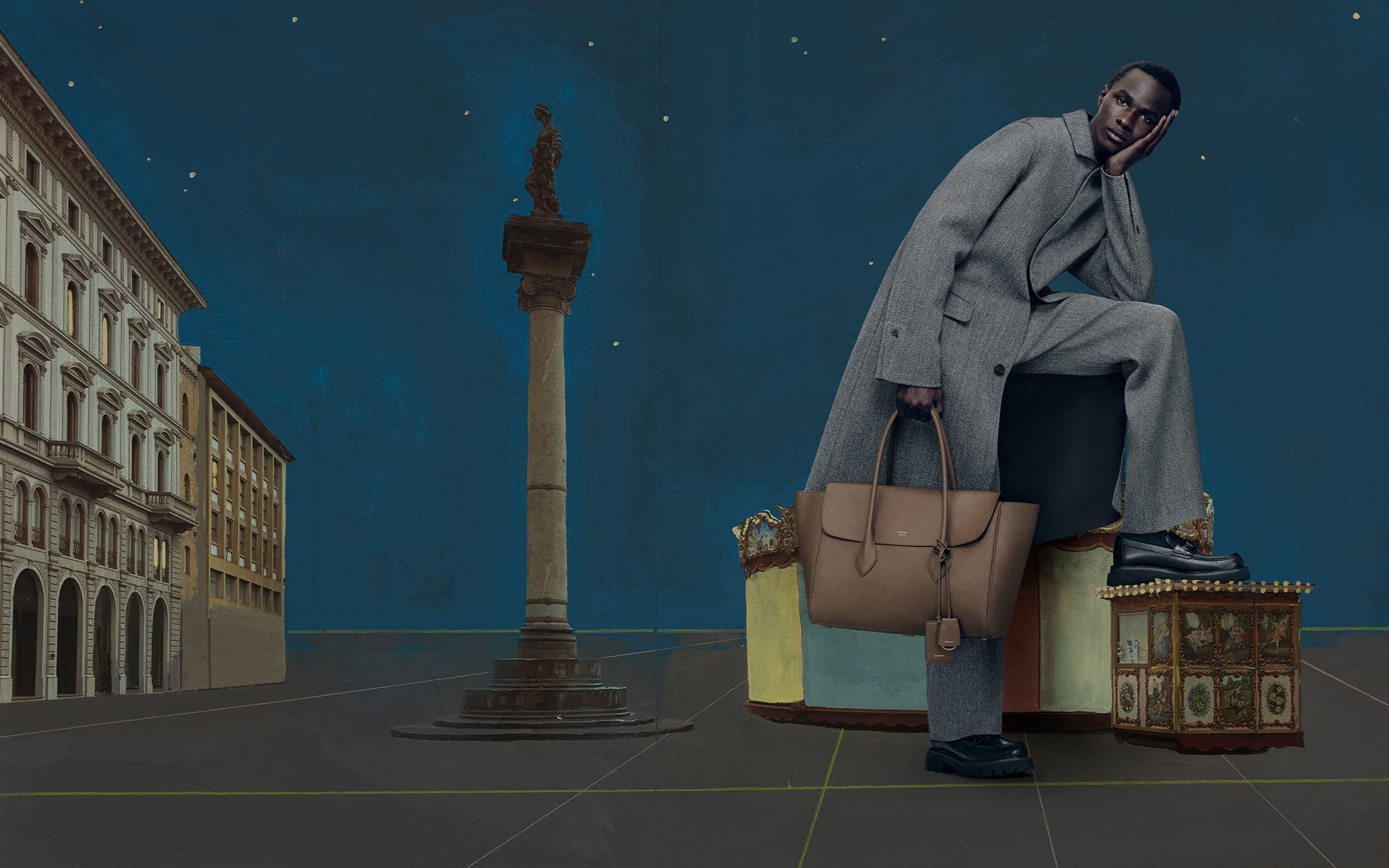 An adult man with dark skin is posing with a handbag, wearing a grey suit with a historical urban background and dark blue sky.