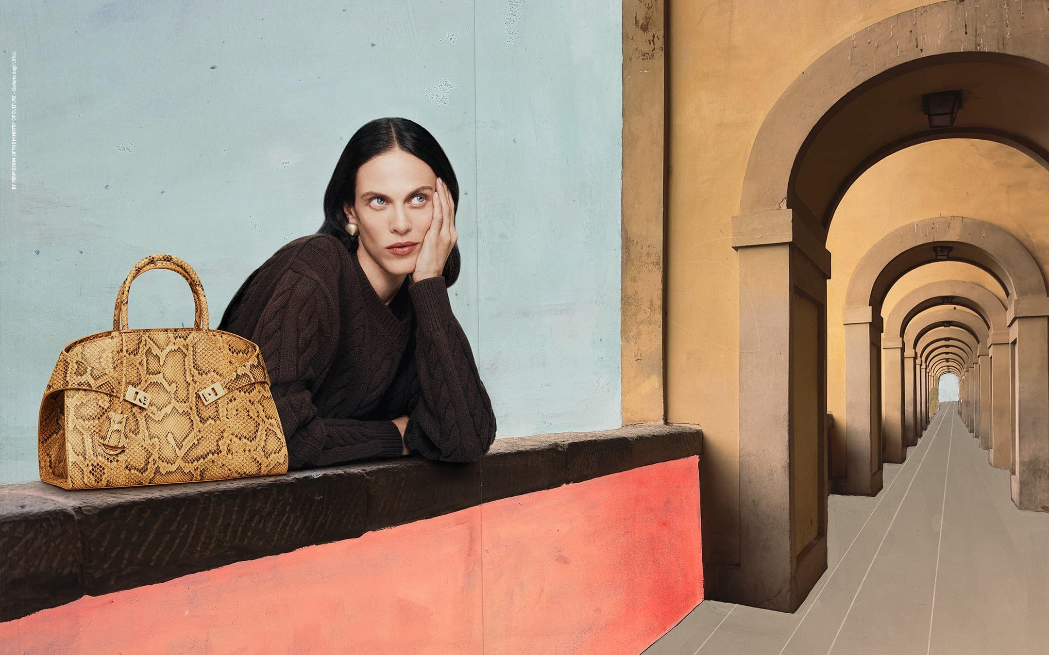 Elegant woman in brown sweater with snakeskin handbag, posing against a background of an arched colonnade. Fashion and style.