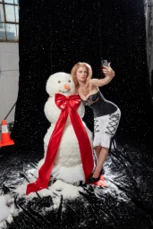 Julia Fox taking a selfie with a large snowman wearing a red bow for the SSENSE Winter 2023 campaign.