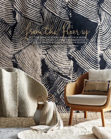 Interior design featuring a wicker chair, patterned rug, and textured throw, creating a cozy and inviting living space with a natural aesthetic.