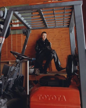 Person seated inside a forklift in a wooden interior for Autre Magazine