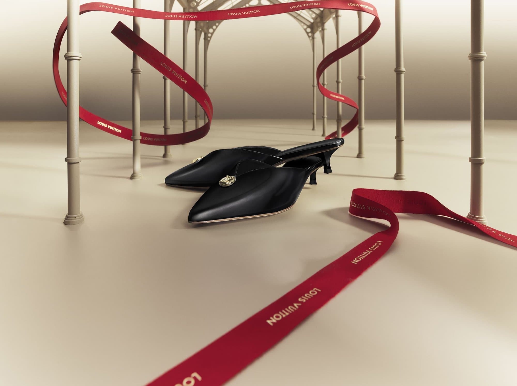 Black mule heels with gem embellishments set against a light backdrop with floating red logo ribbon accents and archway structures.