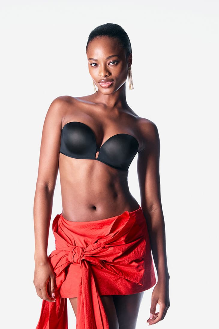 Striking studio portrait of a Black woman in a bra and red skirt, showcasing natural beauty, elegant pose, and clean studio lighting.