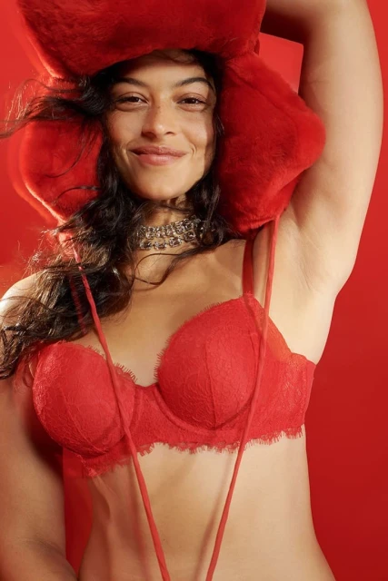 Portrait of an adult woman in a red lace bra and decorative red headpiece against a red background. Studio lighting, fashion.