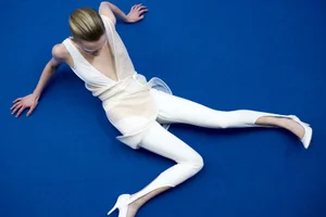 Model wearing a white outfit on a vibrant blue seamless background for The Face Magazine