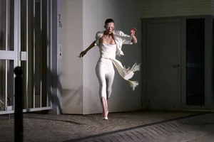 Model in a white outfit running past a building exterior at night for The Face Magazine editorial don't slip up.