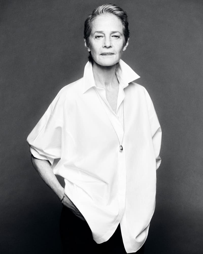 Black and white portrait of an elderly woman with short gray hair in a white button-down shirt, looking at the camera with a neutral expression.