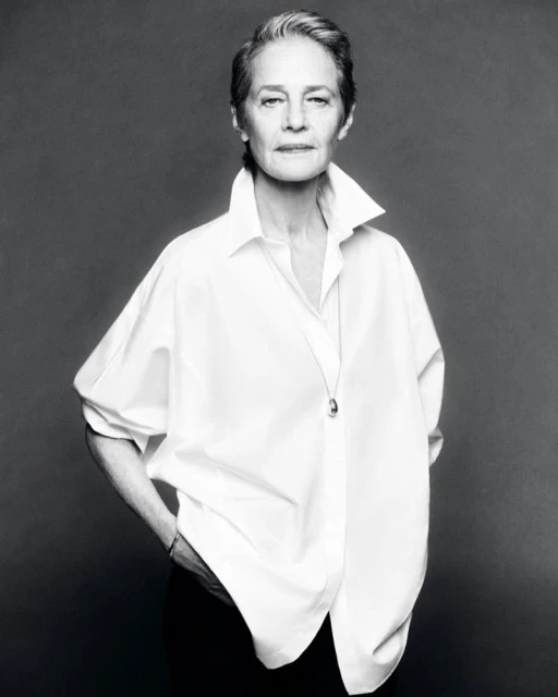 Black and white portrait of an elderly woman with short gray hair in a white button-down shirt, looking at the camera with a neutral expression.