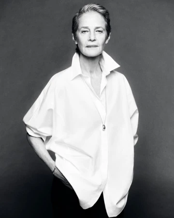 Black and white portrait of an elderly woman with short gray hair in a white button-down shirt, looking at the camera with a neutral expression.