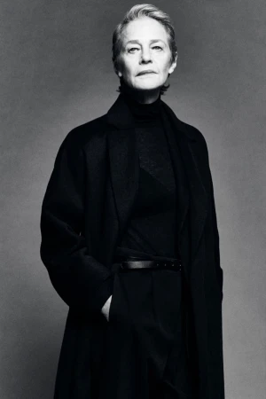 Monochrome studio portrait of actress Charlotte Rampling wearing a black tailored coat over a turtleneck for Massimo Dutti.