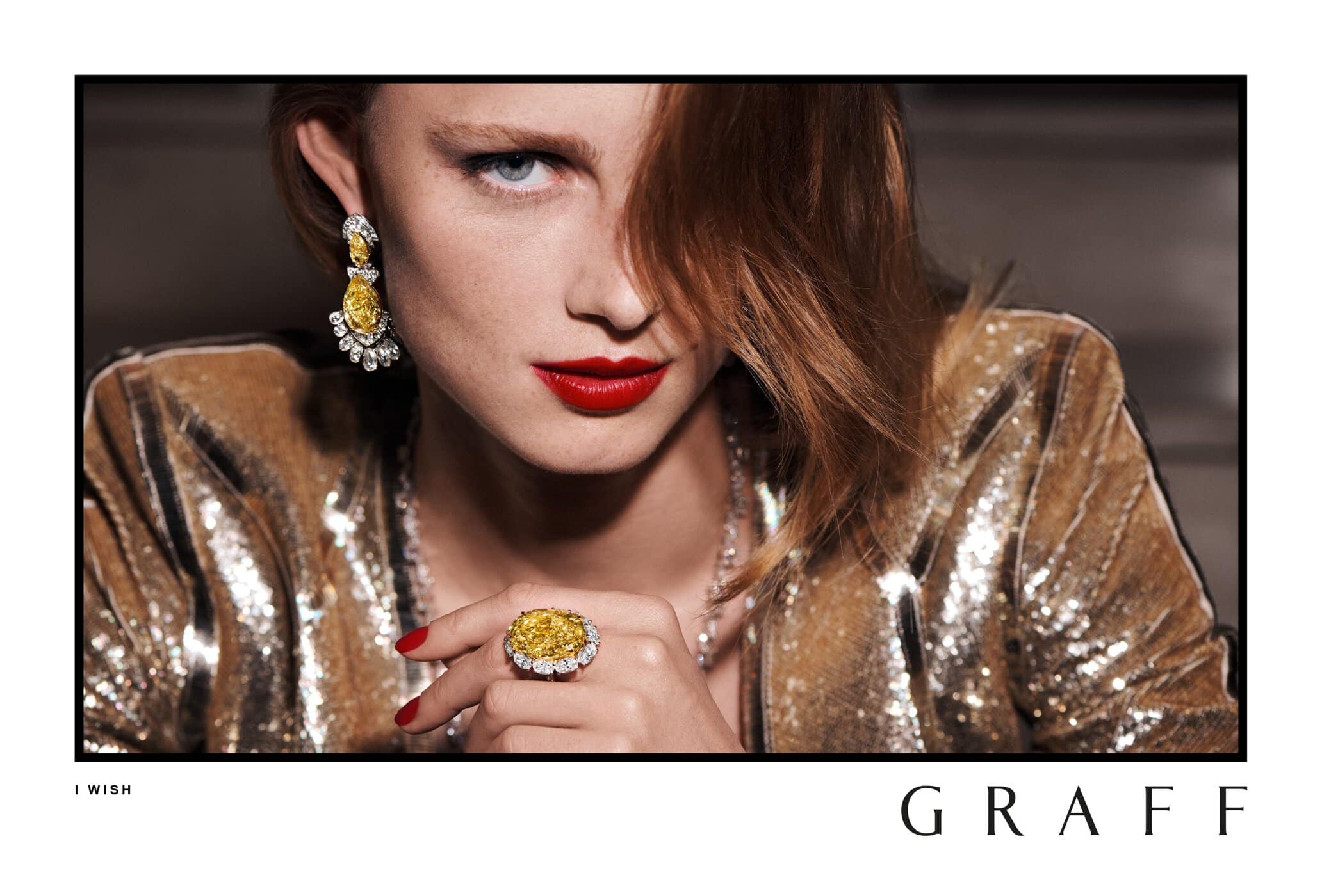 Close-up shot of a model wearing a gold sequin jacket, large yellow diamond ring, and earrings, showcasing a high-end jewelry advertisement.
