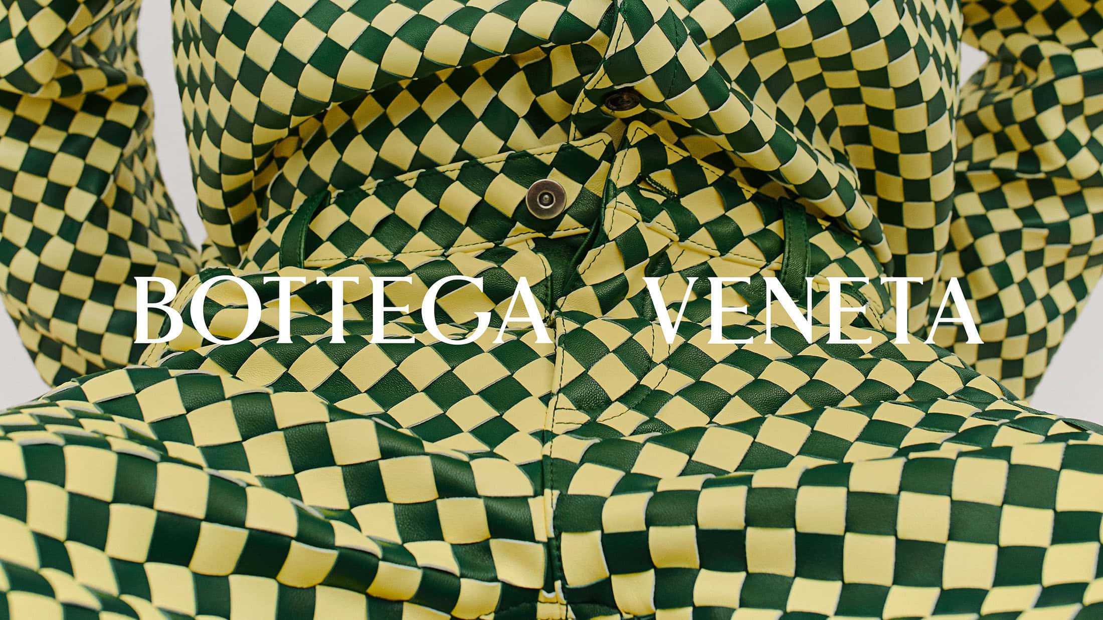 Close-up of a Bottega Veneta jacket featuring a green and yellow checkerboard pattern. Modern fashion design.
