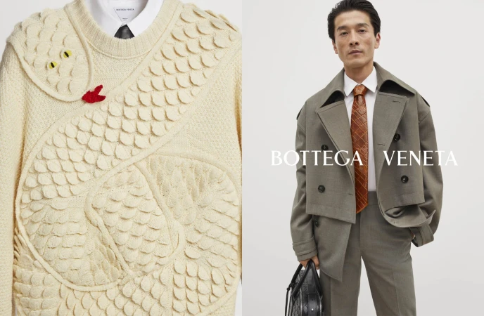Fashion editorial shot showcasing a man in a grey suit with an orange tie and a sweater featuring a snake design against a clean backdrop.