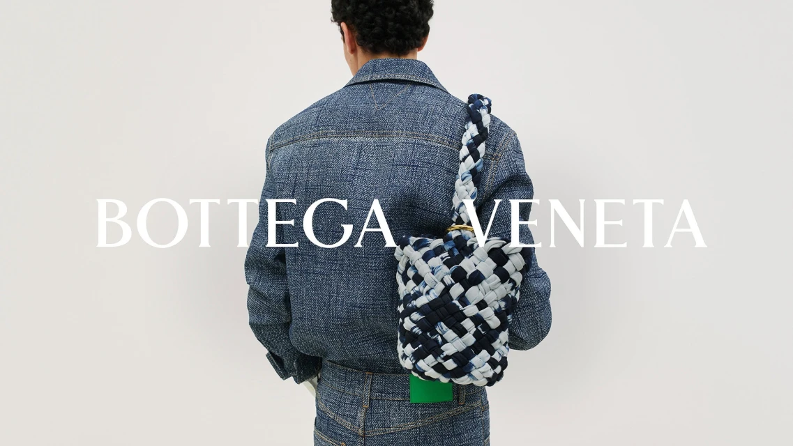 A person wears a denim jacket and pants with a woven bucket bag in front of a white background, with the brand name overlaid.