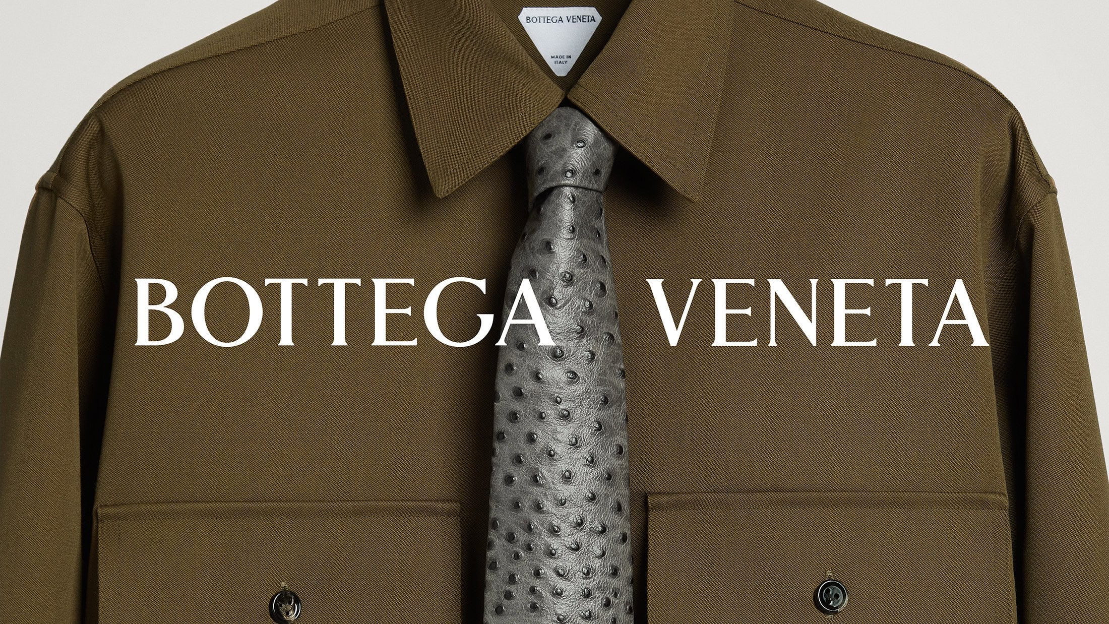 Olive green shirt with a textured grey tie by Bottega Veneta, against a clean, neutral background in a fashion product shot.