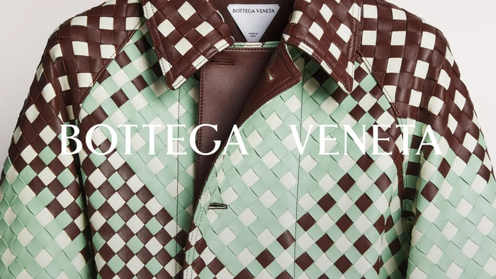 Close-up of a Bottega Veneta woven leather coat in mint green, brown, and cream with white logo typography.